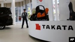 FILE - In this Nov. 6, 2014 file photo, a security guard stands by child seats, manufactured and displayed by Takata Corp. at an automaker's showroom in Tokyo. Japanese automaker Honda Motor Co. expanded its recalls related to defective air bags on Thursd