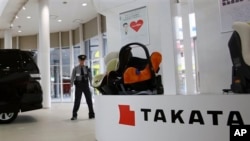 FILE - In this Nov. 6, 2014 file photo, a security guard stands by child seats, manufactured and displayed by Takata Corp. at an automaker's showroom in Tokyo. Japanese automaker Honda Motor Co. expanded its recalls related to defective air bags on Thursd