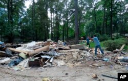 In this Sept. 26, 2017 photo, workers continue clearing debris from the home of Houston resident Chris Slaughter, whose house in the suburb of Kingwood was flooded by over 5 feet during Harvey's torrential rainfall.