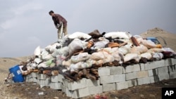 FILE - An Afghan man prepares to set narcotics on fire on the outskirts of Kabul, Oct. 29, 2014. (AP Photo/Massoud Hossaini)
