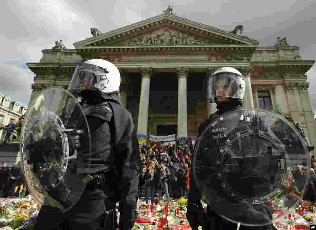 Police in riot gear protect one of the memorials to the victims of the recent Brussels attacks, as right wing demonstrators protest near the Place de la Bourse in Brussels, Belgium.