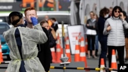 In this April 17, 2020, file photo, medical staff test shoppers who volunteered at a pop-up community COVID-19 testing station at a supermarket carpark in Christchurch, New Zealand. (AP Photo/Mark Baker, File)