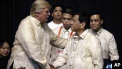 Presiden AS Donald Trump (kiri) berjabat tangan dengan Presiden Filipina Rodrigo Duterte pada acara jamuan makan malam KTT ASEAN di Manila, Minggu (12/11).