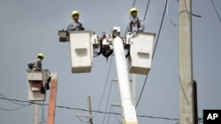 FILE - In this Oct. 19, 2017, photo, a brigade from the Electric Power Authority repairs distribution lines damaged by Hurricane Maria in the Cantera community of San Juan, Puerto Rico.