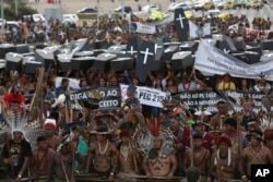 FILE - Indigenous protesters from various ethnic groups carry fake coffins representing indians killed over the demarcation of land, as they demand the demarcation of indigenous lands, outside the National Congress in Brasilia, Brazil, April 25, 2017.