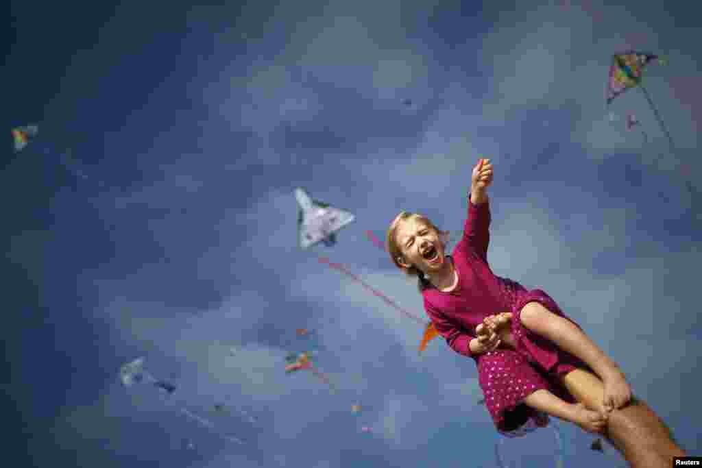 Madeleine Klonoski, 2, sits on her father&#39;s leg at a kite festival in Redondo Beach, California, March 8, 2015.