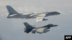 FILE - A Taiwanese F-16 fighter jet flies next to a Chinese H-6 bomber, top, in Taiwan's airspace, in this handout photo taken and released Feb. 10, 2020, by Taiwan's defense ministry.