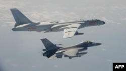 FILE - A Taiwanese F-16 fighter jet flies next to a Chinese H-6 bomber, top, in Taiwan's airspace, in this handout photo taken and released Feb. 10, 2020, by Taiwan's Defense Ministry.