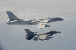 FILE - A Taiwanese F-16 fighter jet flies next to a Chinese H-6 bomber, top, in Taiwan's airspace, in this handout photo taken and released on February 10, 2020, by Taiwan's Defence Ministry.