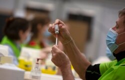 Zdravstveni radnik puni spricu iz bočice vakcine AstraZeneca u Belgiji.