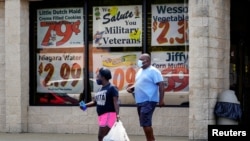 Orang-orang tampak keluar dari Supermarket Piggly Wiggly di mana terdapat beberapa poster yang berisi seruan penghormatan terhadap para veteran terpasang di jendela supermarket yang terletak di Columbus, Georgia, pada 8 September 2020. (Foto: Reuters/Elijah Nouvelage)