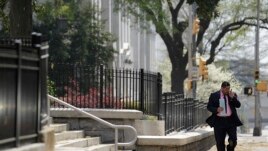 FILE - A pedestrian walks down a street as pollen litters the sidewalk outside the State Capitol Tuesday, March 20, 2012, in Atlanta. (AP Photo/David Goldman)