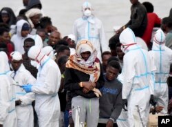 Migrants wait to disembark from Italian Coast Guard vessell "Diciotti" as it docks at the Sicilian port of Catania, southern Italy, June 13, 2018.