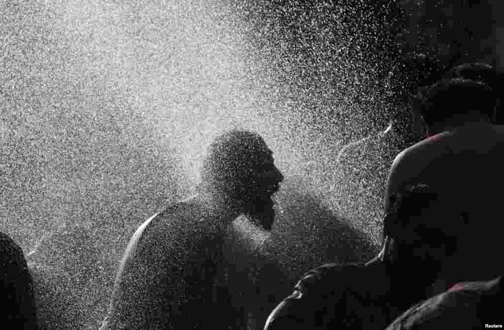 An anti-government protester takes a morning bath with others at a public pump during the Revolution March in Islamabad, Pakistan.