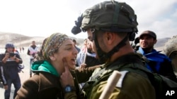FILE - An Israeli soldier argues with a Palestinian protester as they try to block a highway between Jerusalem and the Dead Sea near the West Bank town of Jericho. 