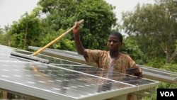 A Beninese man cleans one of the solar panels that has electrified his village (Courtesy SELF)