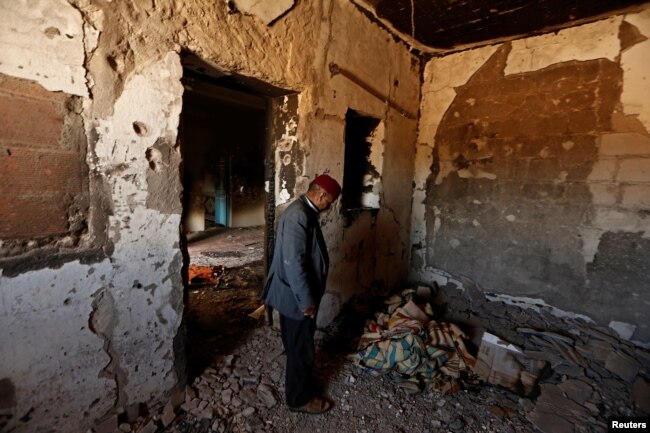 FILE - Hamid Ishi stands in his house, which was taken over by Islamic State jihadists and damaged during fighting with government forces, in Ben Guerdane, Tunisia, April 10, 2016.
