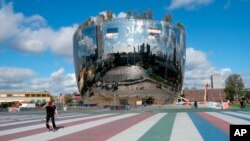 A skateboarder in front of the new Depot Boijmans Van Beuningen in Rotterdam, Netherlands, Sept. 24, 2020. The Museum Boijmans Van Beuningen in Rotterdam has a shimmering new depot that opens up the institution's engine room to the public. (AP Photo/Mike Corder)