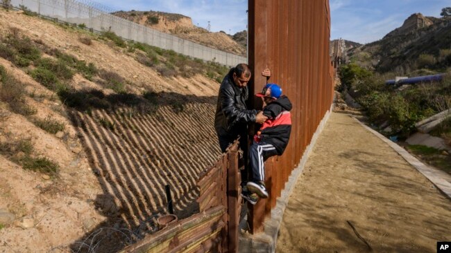 2018年12月22日洪都拉斯移民帮助他儿子攀登美国边境围栏从墨西哥蒂华纳进入美国加利福尼亚州圣迭戈