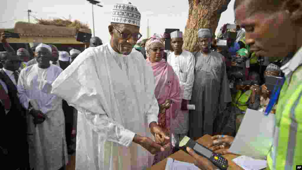 Le candidat de l&#39;opposition le général Muhammadu Buhari, au centre, arrive pour faire valider sa carte de vote à travers un lecteur d&#39;empreintes digitales, avant de revenir voter plus tard dans la journée, dans sa ville natale de Daura, Nigeria Saturday, samedi 28 mars 2015.