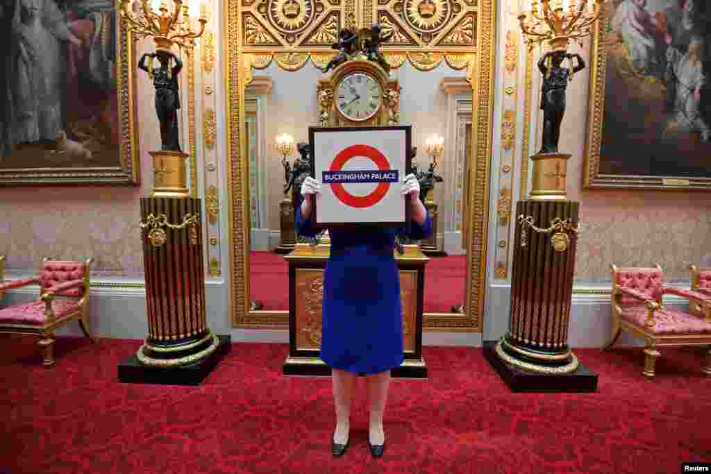 Sally Goodsir, Assistant Curator of Decorative Arts, holds a London Underground sign presented to Queen Elizabeth in 2010, one of the items of the Royal Gifts exhibition which goes on public display on July 22 at the Summer Opening of the State Rooms at Buckingham Palace, London.