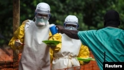 FILE - Medical staff working with Medecins Sans Frontieres (Doctors Without Borders) in July 2014 take food to patients in the isolation area of an Ebola treatment center in Sierra Leone. 
