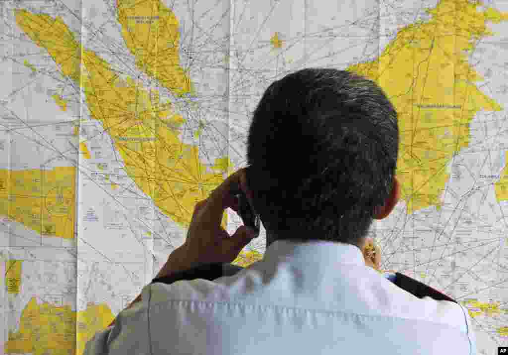 سورابایا کے ہوائی اڈے پر قائم کیے جانے والے &#39;ہنگامی مرکز&#39; پر ایک افسر انڈونیشیا کے نقشے کا معائنہ کر رہا ہے۔