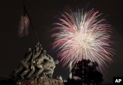 The United States Marine Corps War Memorial, better known as the Iwo Jima Memorial, in Arlington, Virginia, on July 4, 2011, as fireworks burst over Washington. The Washington Monument and the Capitol are in the distance.