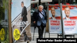 FILE - A man passes by presidential election campaign posters of Alexander Van der Bellen (L), supported by the Greens, reading "A president who unites" and Norbert Hofer of the Freedom Party (FPOe), reading "The voice of reason" in Vienna, Austria, May 19, 2016.