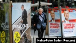 Seorang pria berjalan melewati poster kampanye pilpres Alexander Van der Bellen, kandidat dari Partai Hijau (kiri), dan Norbert Hofer, capres dari Partai Kebebasan (FPOe), di WIna, Austria, 19 Mei 2016 (Foto: dok).