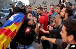 A regional policeman removes a protester with an "estelada" or independence flag, during a protest against a search for propaganda supporting Catalonia's independence referendum at the private postal service company Unipost in Terrassa, Spain, Sept. 19, 2017.