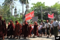 Hard-line Buddhists walk by a mosque during a protest march, led by Rakhine State's dominant Arakan National Party, against the government's plan to give citizenship to some persecuted Rohingya Muslims, March 19, 2017, in Myanmar.
