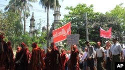 FILE - Hard-line Buddhists walk by a mosque during a protest march, led by Rakhine State's dominant Arakan National Party, against the government's plan to give citizenship to some persecuted Rohingya Muslims, March 19, 2017.