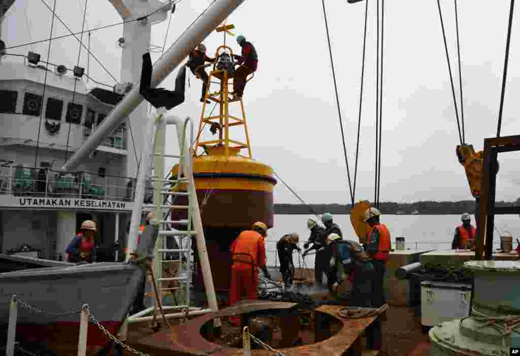 Des membres de l&#39;équipage du navire KN Jadayat prépare une bouée de balise pour commencer les opérations de recherche de l&#39;épave du vol 8501 d&#39;AirAsie, au Port Kumai dans Pangkalan Bune l&#39;Indonésie, le 5 janvier 2015.