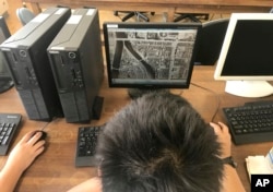 A member of the computation skill research club at Fukuyama Technical High School looks at an archive material of Hiroshima city to edit buildings on computer graphic software