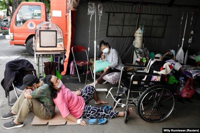 Seorang pasien COVID-19 beristirahat di tanah di luar tenda darurat yang didirikan di luar rumah sakit di tengah lonjakan kasus COVID-19 di Bekasi, 25 Juni 2021. (Foto: Willy Kurniawan/Reuters)