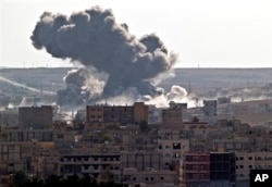 FILE - Smoke rises over the Syrian city of Kobani, following a US led coalition airstrike, seen from outside Suruc, on the Turkey-Syria border Monday, Nov. 10, 2014. Kobani, also known as Ayn Arab, and its surrounding areas, has been under assault by extremists