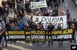 FILE - Civil police demand better labor conditions as they carry a banner that reads in Portuguese "The priority of the police is the people, the priority of the government is the Olympics" in Rio de Janeiro, Brazil, June 27, 2016.
