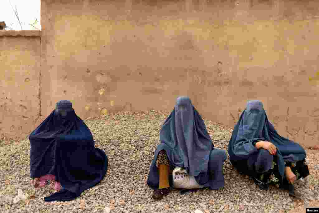 Women wearing burqas sit on the side of a road in Kabul, Afghanistan, Oct. 26, 2021.