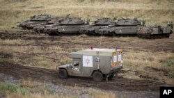 Sebuah ambulans militer Israel melewati tank-tank yang disiagakan di Dataran Tinggi Golan, dekat perbatasan Suriah, Kamis (10/5).