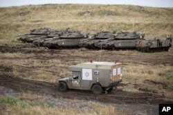 Una ambulancia militar israelí pasa frente a un grupo de tanques en las Alturas del Golán, territorio controlado por Israel, cerca de la frontera. Mayo 10, 2018.
