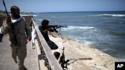 Rebel fighters shoot at what is allegedly Moammar Gadhafi's beach house in Tripoli, August 29, 2011