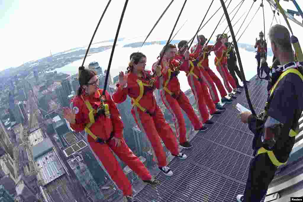 Six new Canadian citizens take their oath of citizenship while harnessed on the CN Tower&#39;s &quot;Edgewalk&quot; 356 meters (1,168 feet) above Toronto, Ontario, in a still image from video, Oct. 9, 2018.