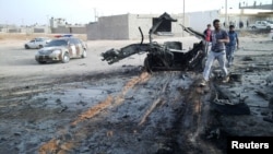 People inspect the site after a car bomb hit the convoy of Abdel-Razeq Nathouri, the chief of staff of the eastern Libyan military, outside Benghazi, Libya, April 18, 2018. 