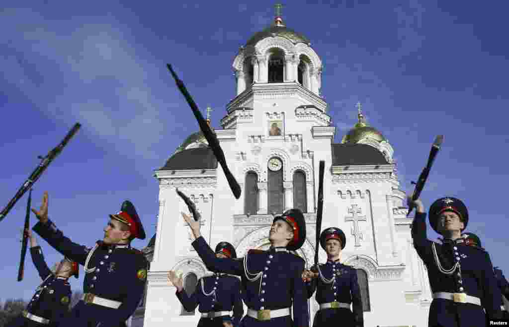 Cossack cadets toss their rifles as they practice for an upcoming performance to mark the 130th anniversary of the founding of the Novocherkassk Cossack cadet corps, outside a cathedral in the southern Russian city of Novocherkassk. 