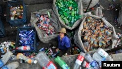 A laborer looks up as she sorts plastic bottles at a garbage recycling centre in Hefei, Anhui province, China, May 20, 2014. 