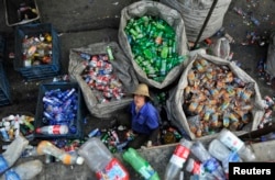 A laborer looks up as she sorts plastic bottles at a garbage recycling center in Hefei, Anhui province, China, May 20, 2014.