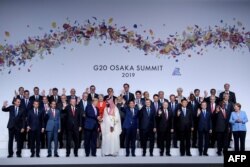 US President Donald Trump (centre L) and Saudi Arabia's Crown Prince Mohammed bin Salman (centre R) shake hands during a group photo of members during the G20 Summit at the INTEX Osaka in Osaka on June 28, 2019.