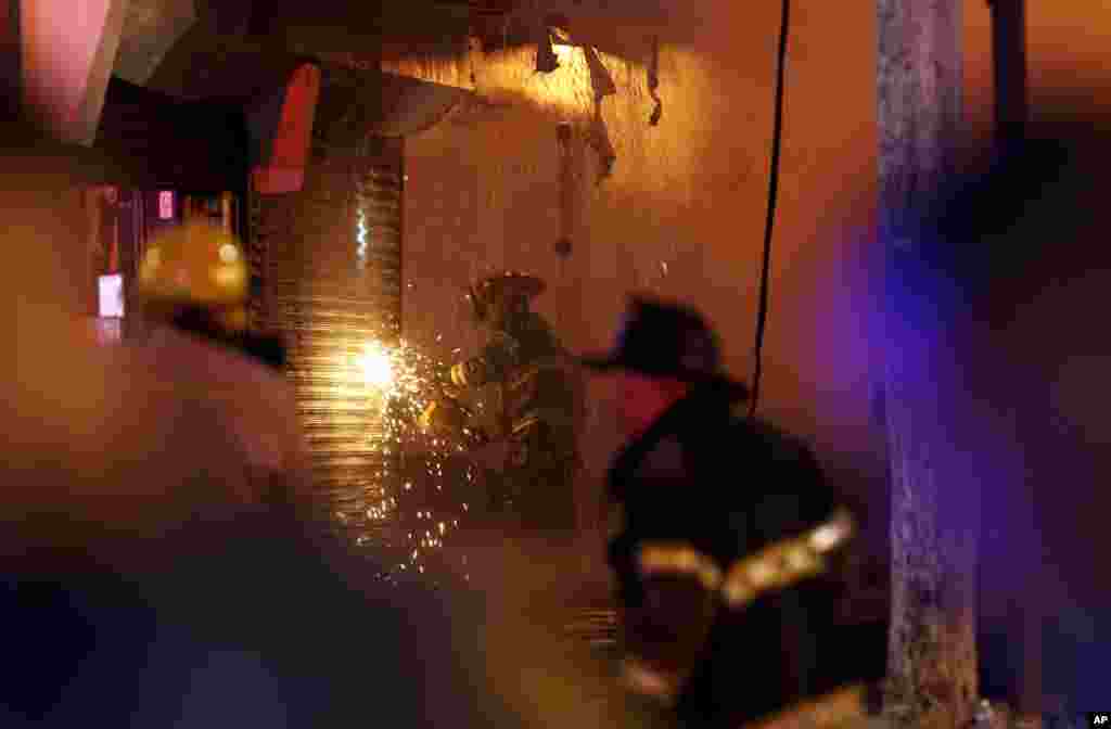 A firefighter saws through a metal wall on a building while battling a fire at the Seaside Park boardwalk on Sept. 12, 2013, in Seaside Park, N.J.