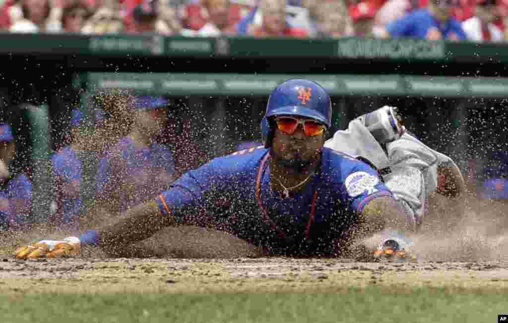 New York Mets' Jordany Valdespin slides head first into home plate to score on an RBI double by Daniel Murphy during the third inning of a baseball game against the St. Louis Cardinals in St. Louis, May 16, 2013.